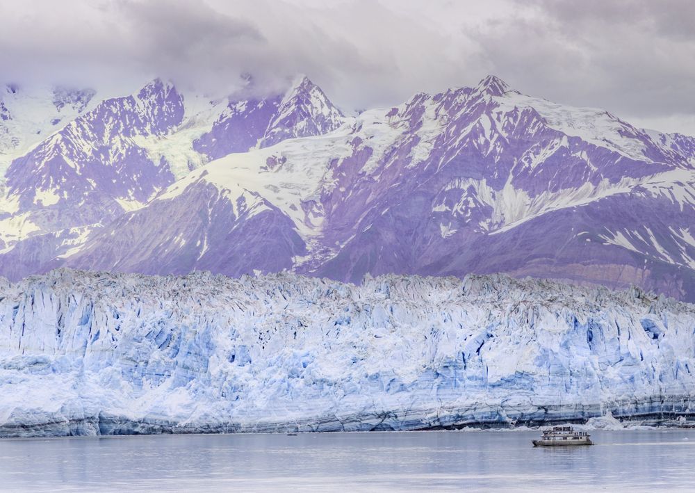A tour boat sailing past the Hubbard Glacier and Mountains in Alaska.