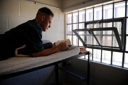 A Fremont Correctional Facility inmate reading a book on the top bunk of his cell.