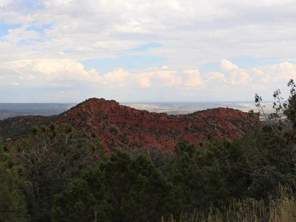 A beautiful rust colored hill against a blue, cloudy sky.