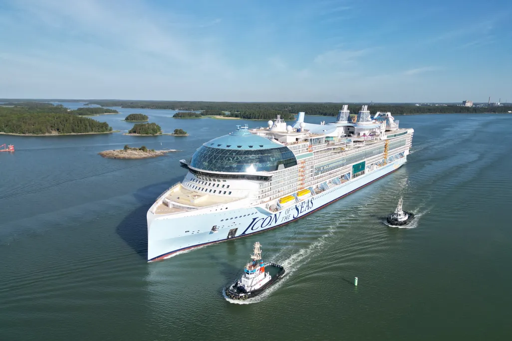 Large cruise ship with tug boats in the water nearby