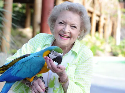 Betty White poses with a parrot at the Los Angeles Zoo in 2014.