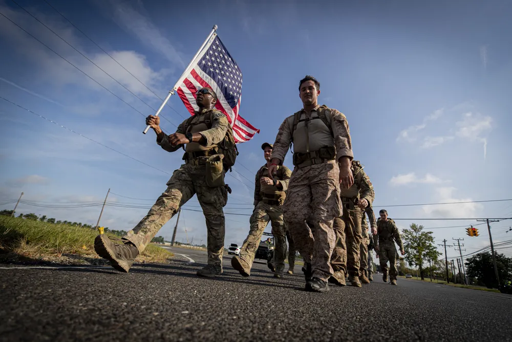 soldiers march carrying an American flag