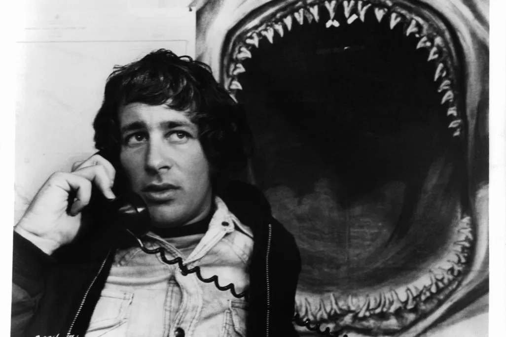 spielberg on the phone in front of a shark jaw