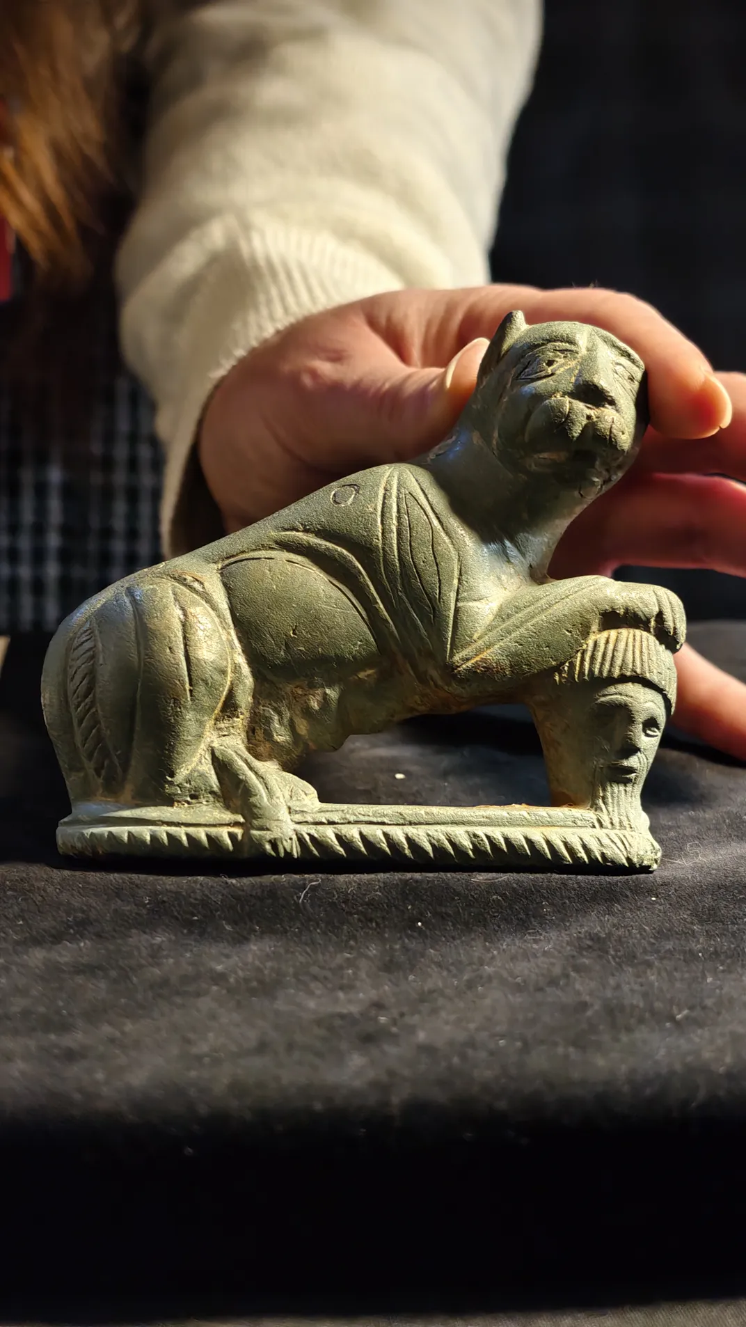 A person's hand holding a figurine of a cat