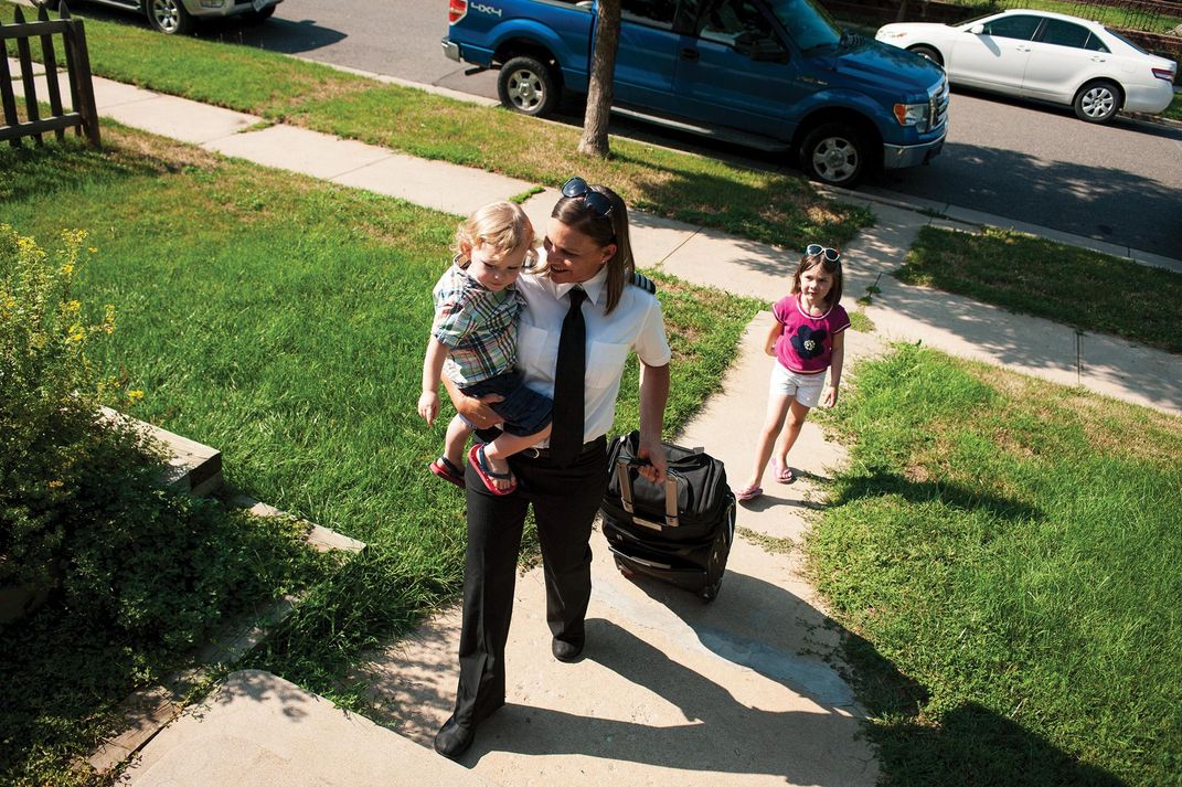 Brandy Beck holds a child and pulls a suitcase