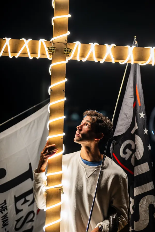 A man holding a cross and a flag thumbnail