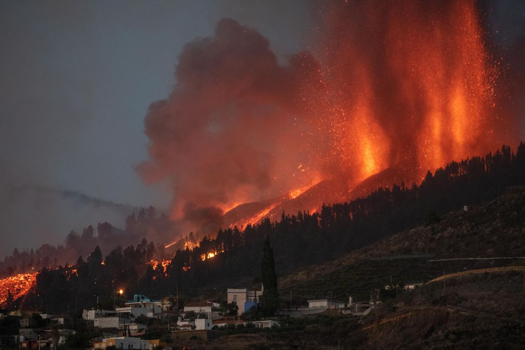 An image of a volcano on La Palma Island spewing lava near a village.