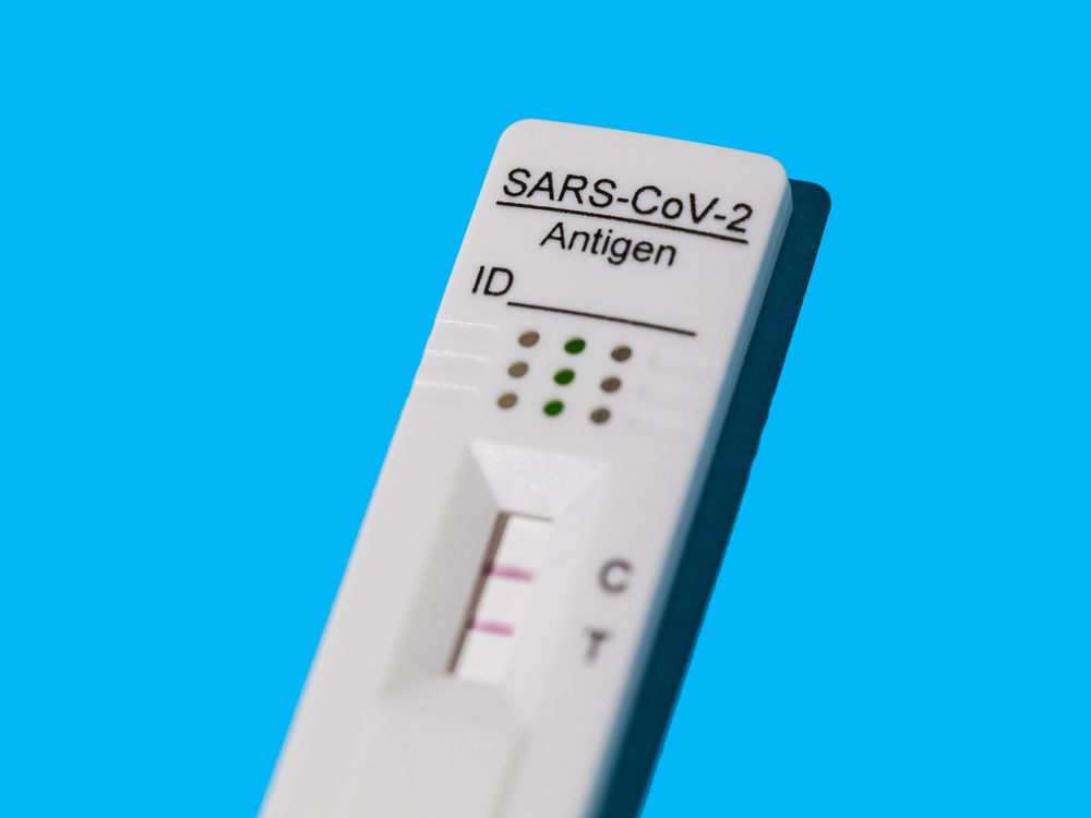 An image of a positive Covid-19 antigen test on a blue background