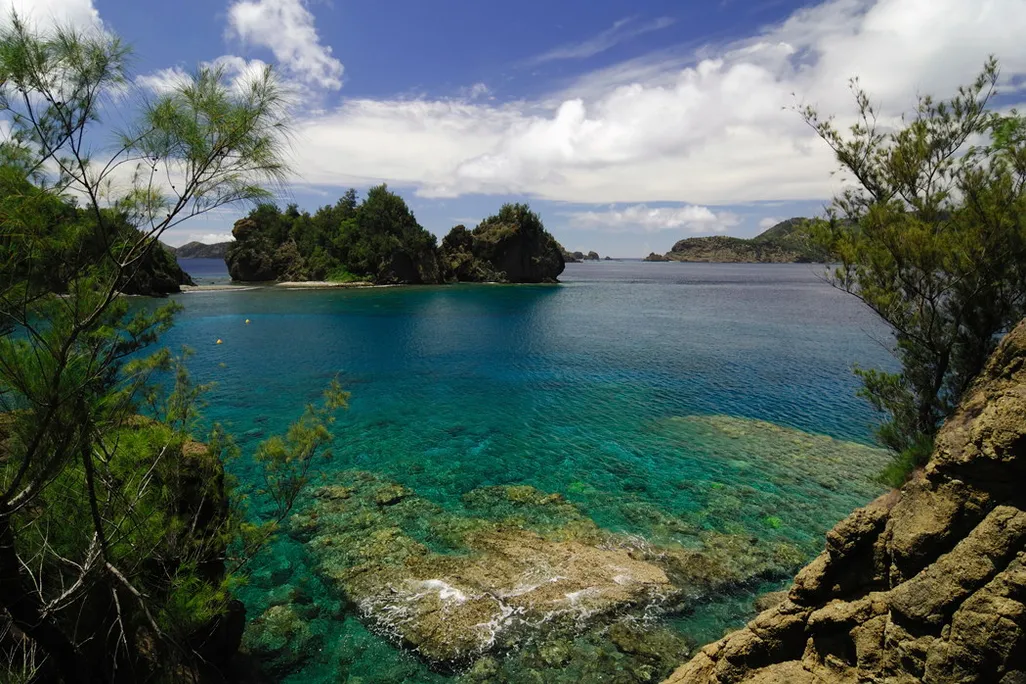 A landscape photo of Japan's Bonin Islands. Rock formations jut up from the clear, bright water.
