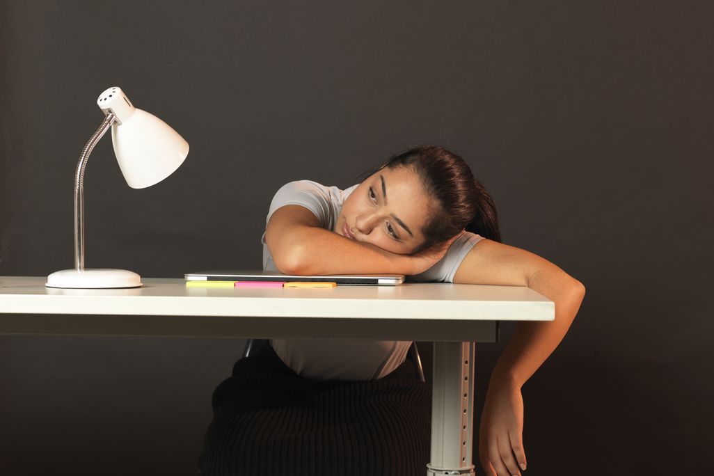 a woman resting her head on a desk and staring into space