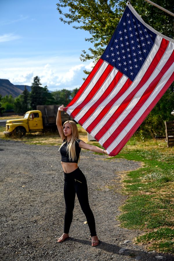 Patriot American woman proudly holding the American flag on her land thumbnail