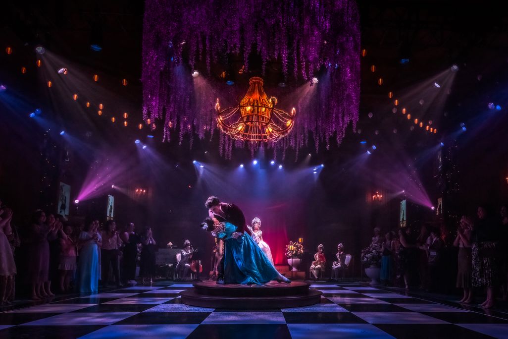 couple in Regency attire doing a dip in the middle of a dramatically lit ballroom