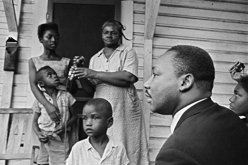 Dr. Martin Luther King Jr. , chats with African-Americans during a door-to-door campaign in 1964.