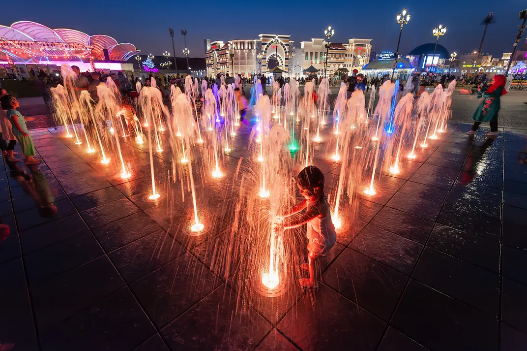 Children play in water fountains at night