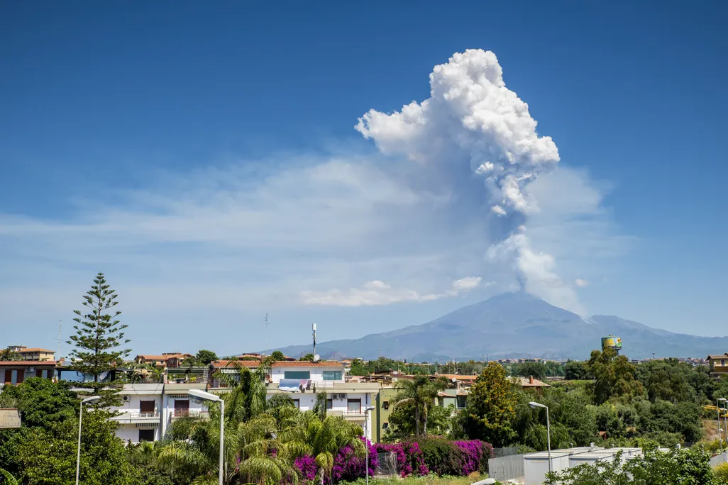 a plume of ash rises from Mount Etna in the distance on Sicily