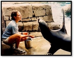 Mandy Fischer offers a reward to a sea lion that is raising one flipper
