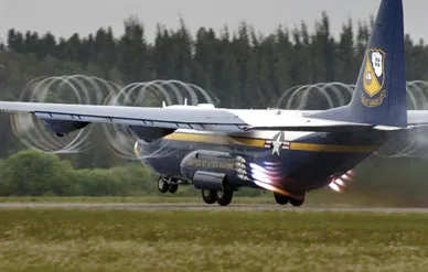 Resplendent in U.S. Navy Blue Angels livery, a Marine Corps C-130T fires its jet-assisted takeoff bottles, which add 8,000 pounds of thrust for a super-short takeoff.
