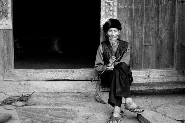 An old Dong ethnic minority man sits in front of his house. thumbnail