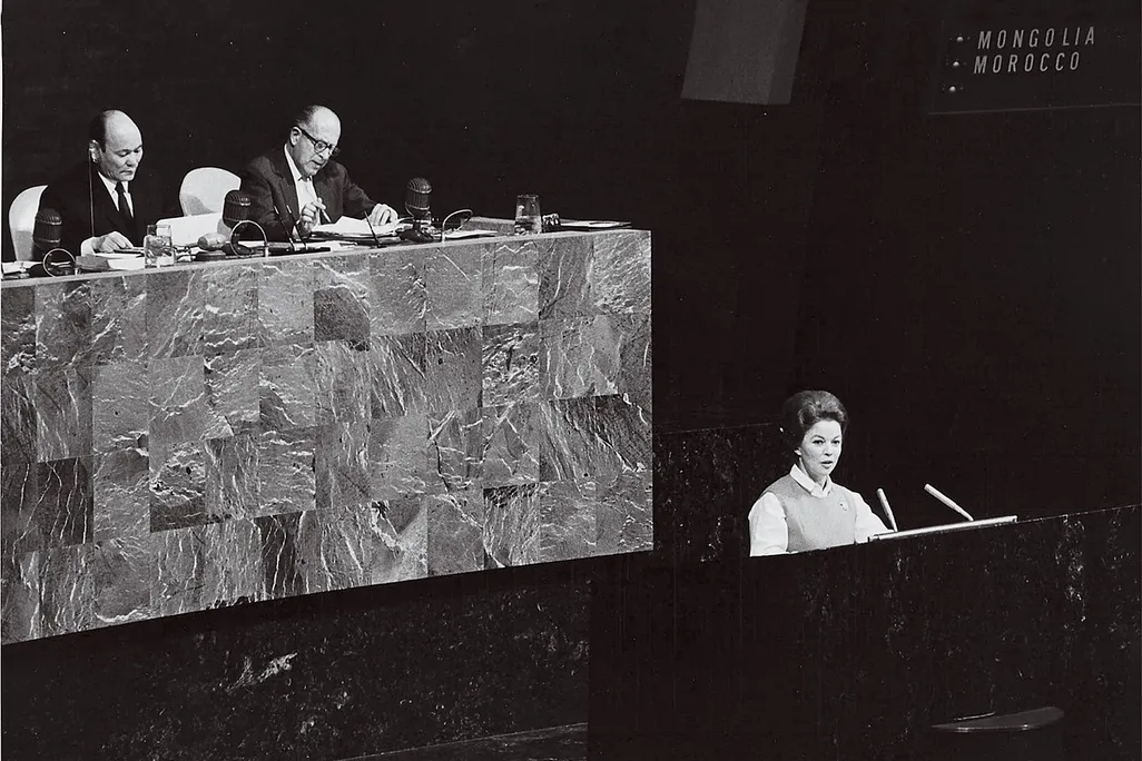 a black and white photo of Shirley Temple Black speaking at a microphone