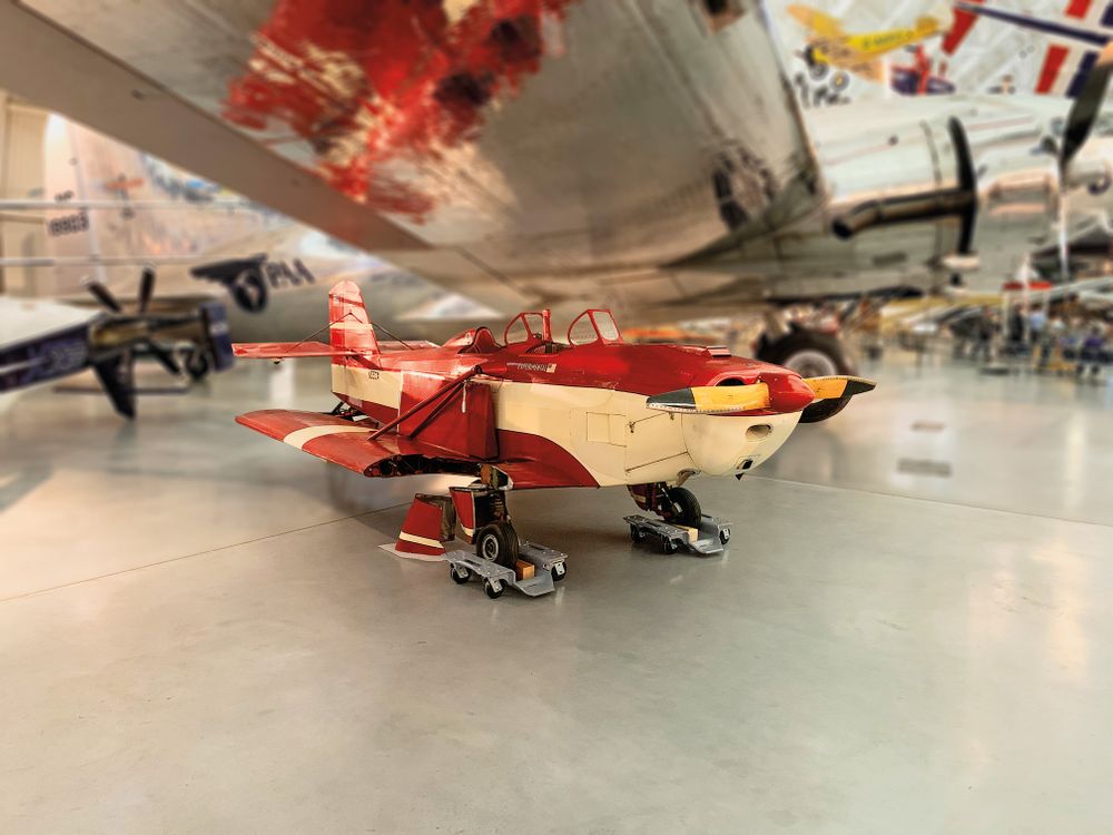 a red vintage airplane sits in an hanger