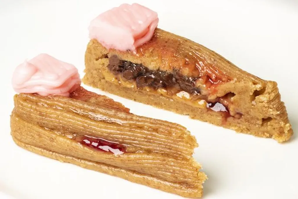 A 3D-printed slice of cake cut in half, with a graham cracker paste base and pink frosting on top.