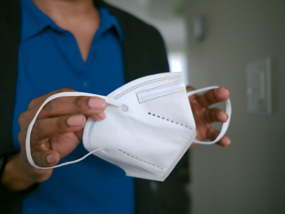 A Black woman holding an N95 face mask in her hands