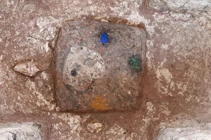 A stone with blue, green and yellow dots on it