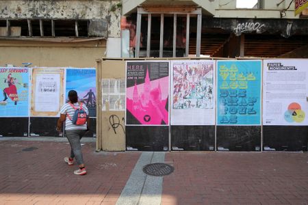 A person looking at a wall of posters in front of a building under construction