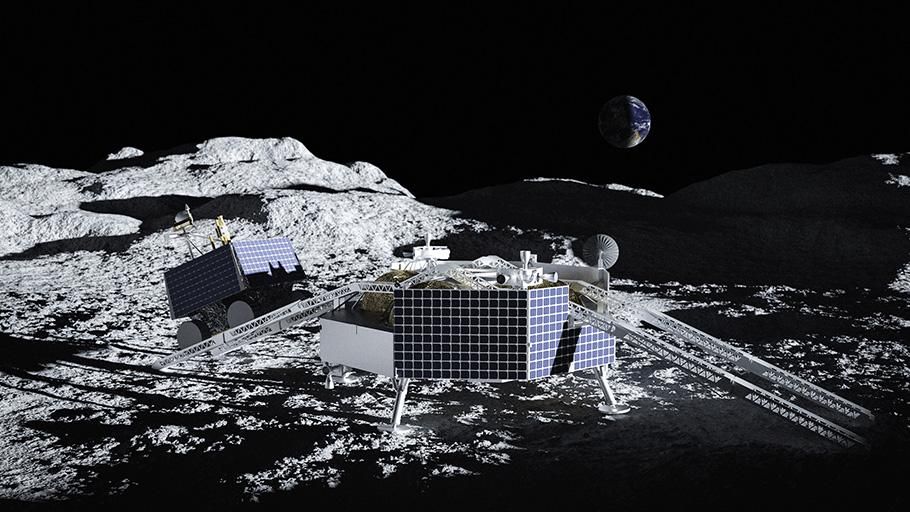 A grey, boxy lander sits on the sunlit lunar surface near some large hills. Two ramps extend from the lander, and a smaller rover rolls down one of them.