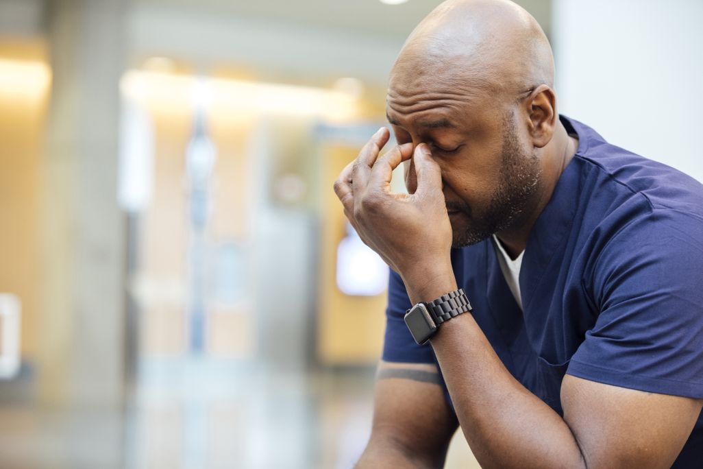 A stressed person pinches the bridge of their nose