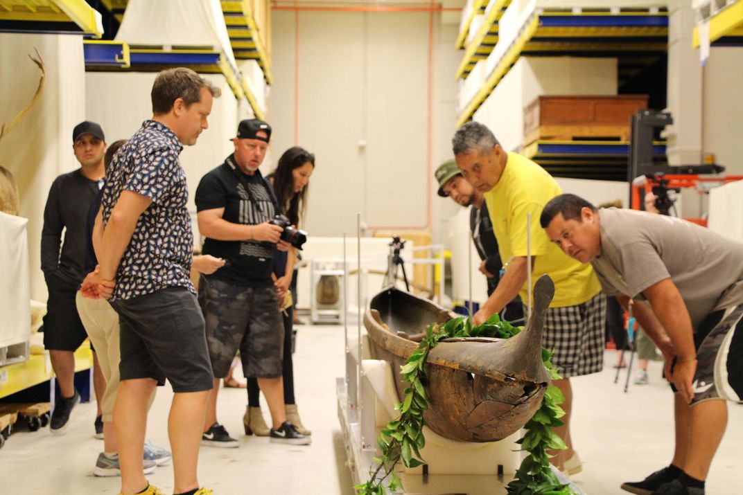 A group of people looking at a historic canoe.