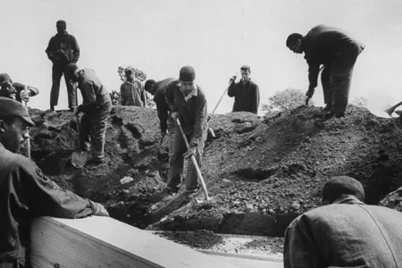 Prisoners bury a wooden coffin on Hart Island.