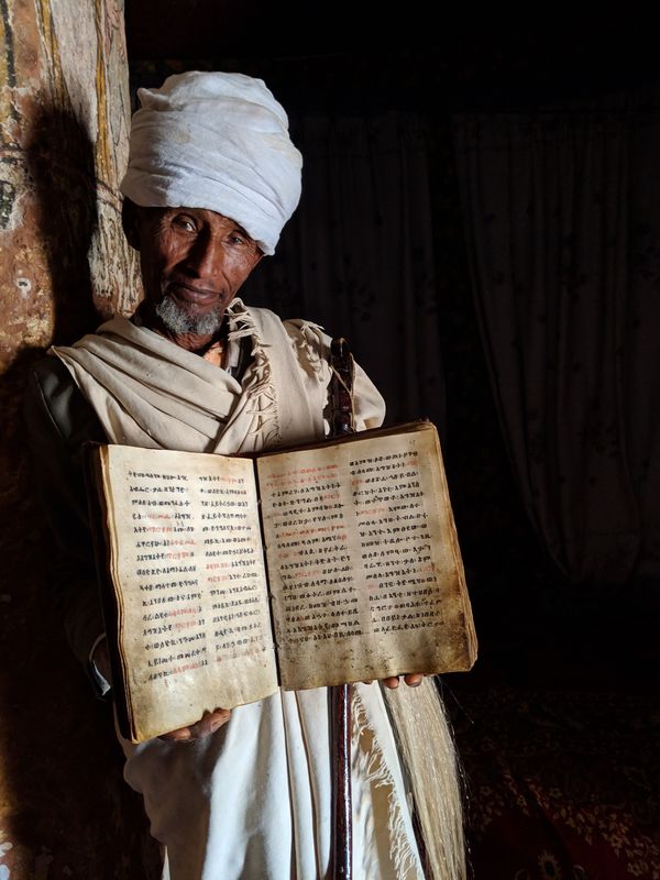 African priest holding bible thumbnail