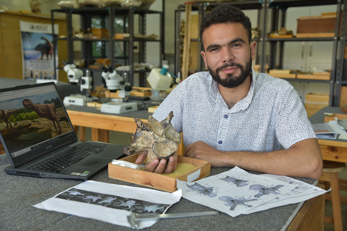 An image of graduate student, Belal Salem holding a neck vertebra of a abelisaurid theropod