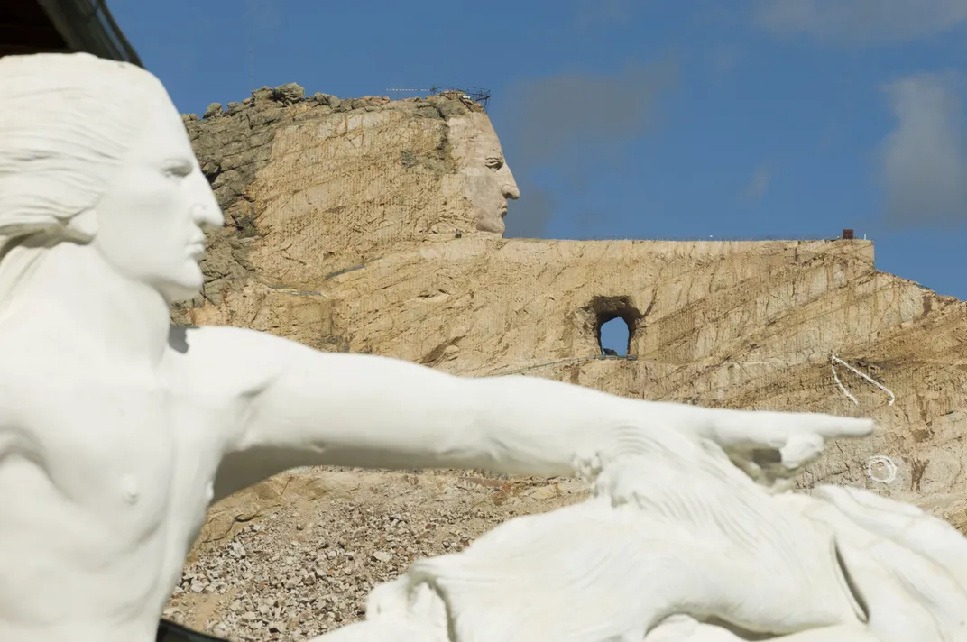 Un sculpteur géant creusé dans une montagne avec un modèle miniature au premier plan.