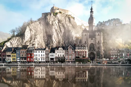The Citadel of Dinant, a clifftop fortress more than 500 years old, looms above colorful buildings lining the Meuse River.