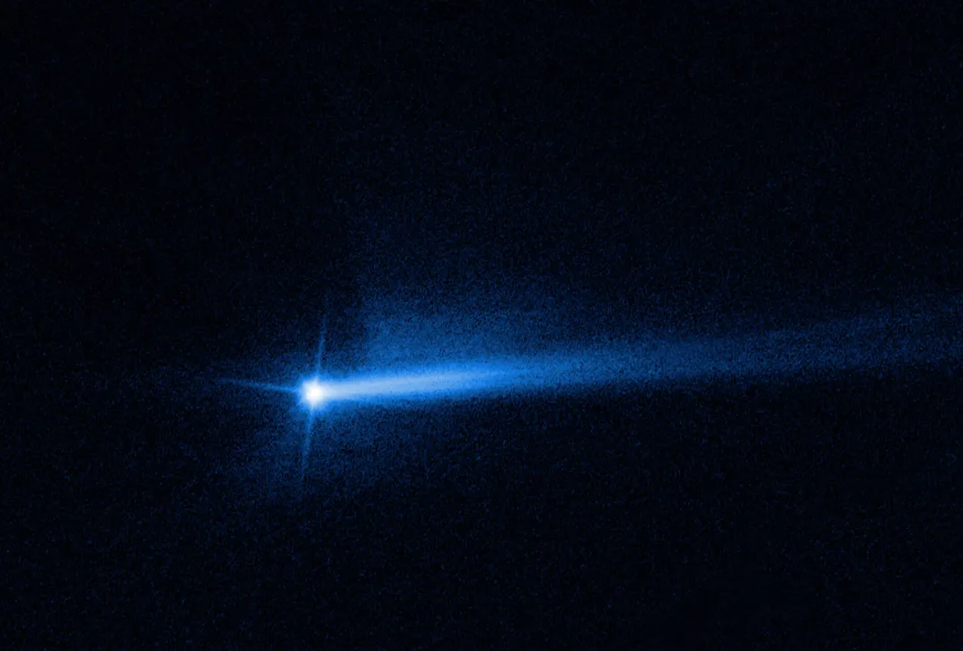 a blue orb with a few diffraction spikes coming from it, and two tails of little blue dots on a black background