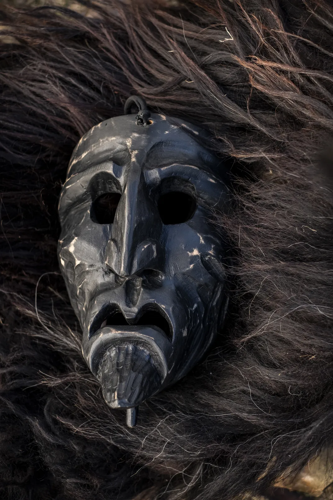An old and worn Mamuthone mask atop a sheepskin Mamuthone cloak.