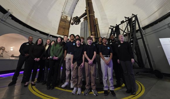 A group smile in front of the Great Refractor telescope