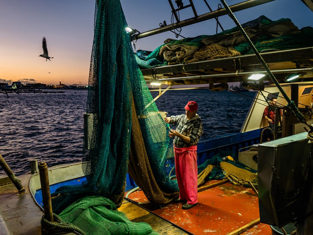 Fisherman fixing a net on a boat at dusk