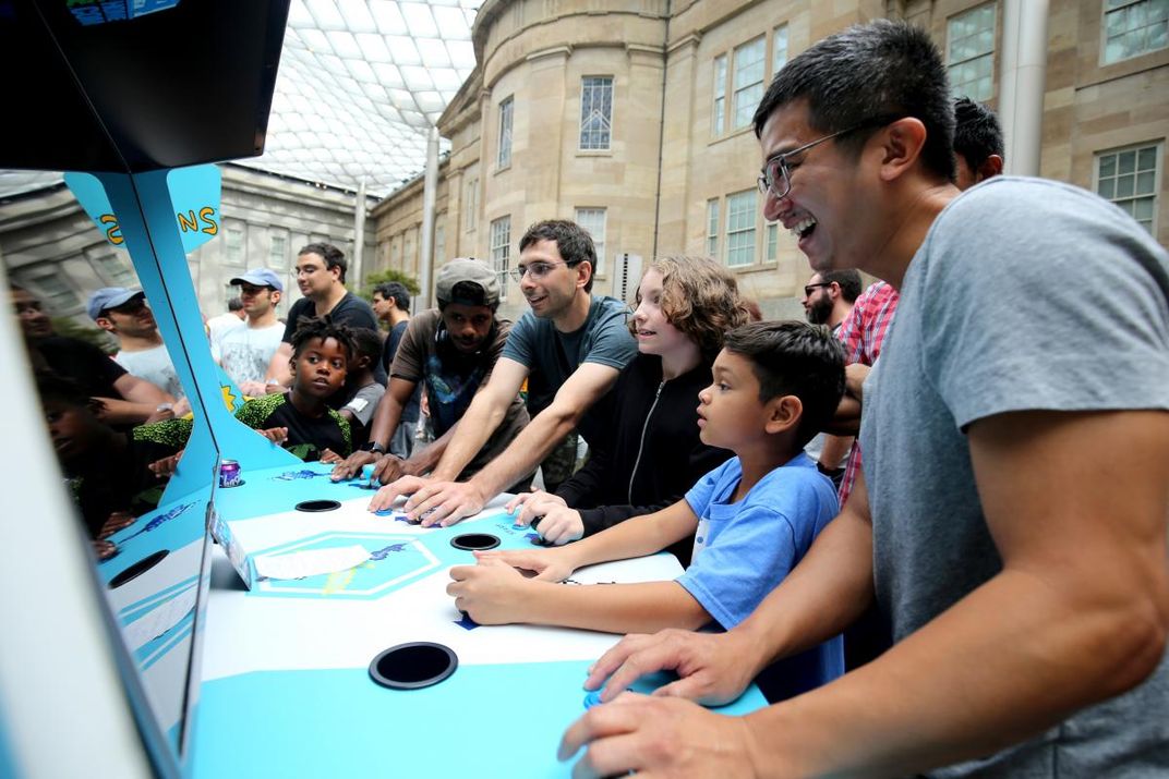 A photograph of six individuals playing a video game together.