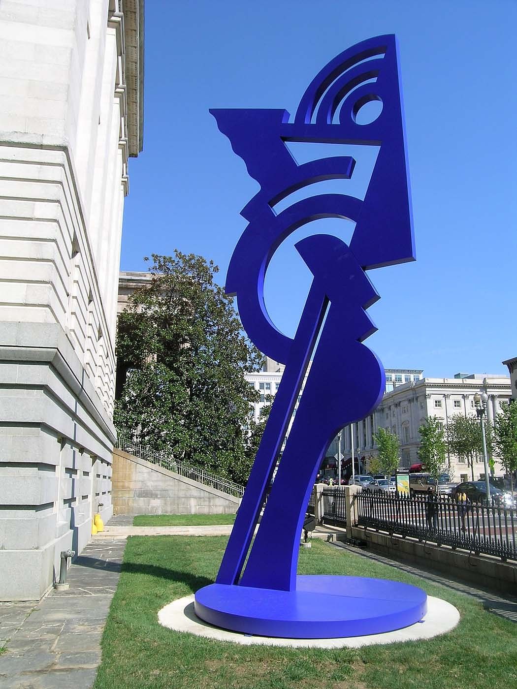 A large-scale blue sculpture of an angular, abstracted head installed outdoors