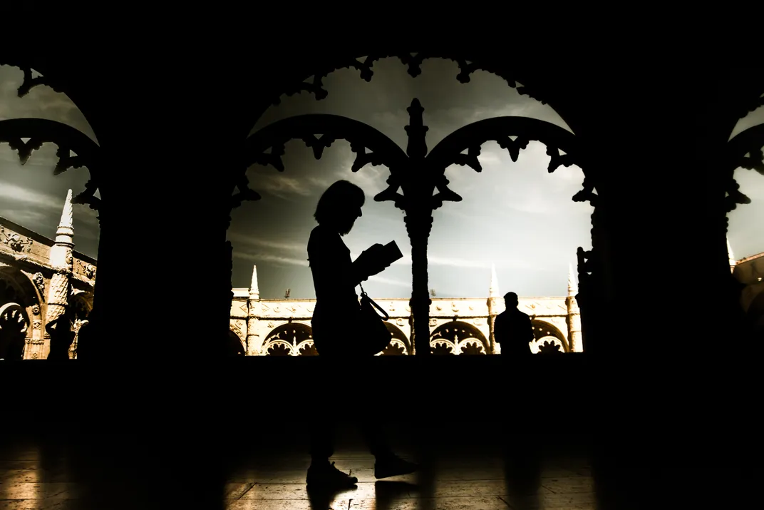 A woman walks along the pathways of the Jerónimos Monastery