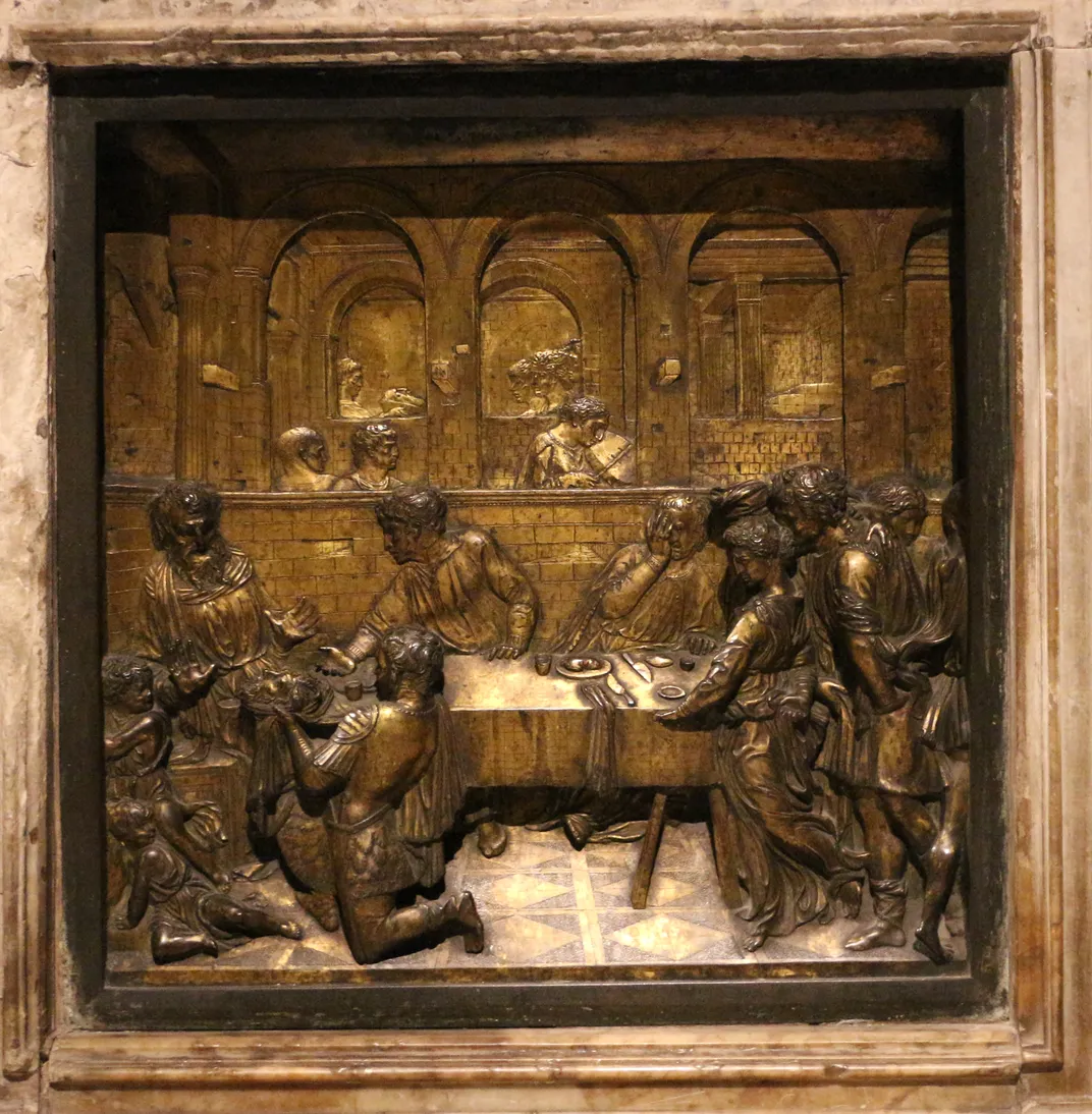 A bronze sculpted relief of a feast scene, with several arches leading into a maze of rooms and corridors behind that emphasize perspective