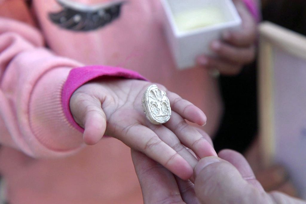 Little girl's hand holding a small decorative stone