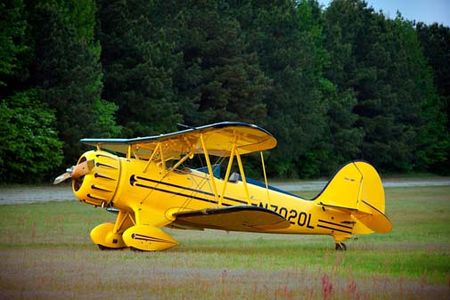 A classic WACO biplane in the grass at Briscoe Field in Lawrenceville, Georgia.  1999 WACO Classic Aircraft Corporation, model YMF-5C, with a 275 horsepower Jacobs radial engine.
