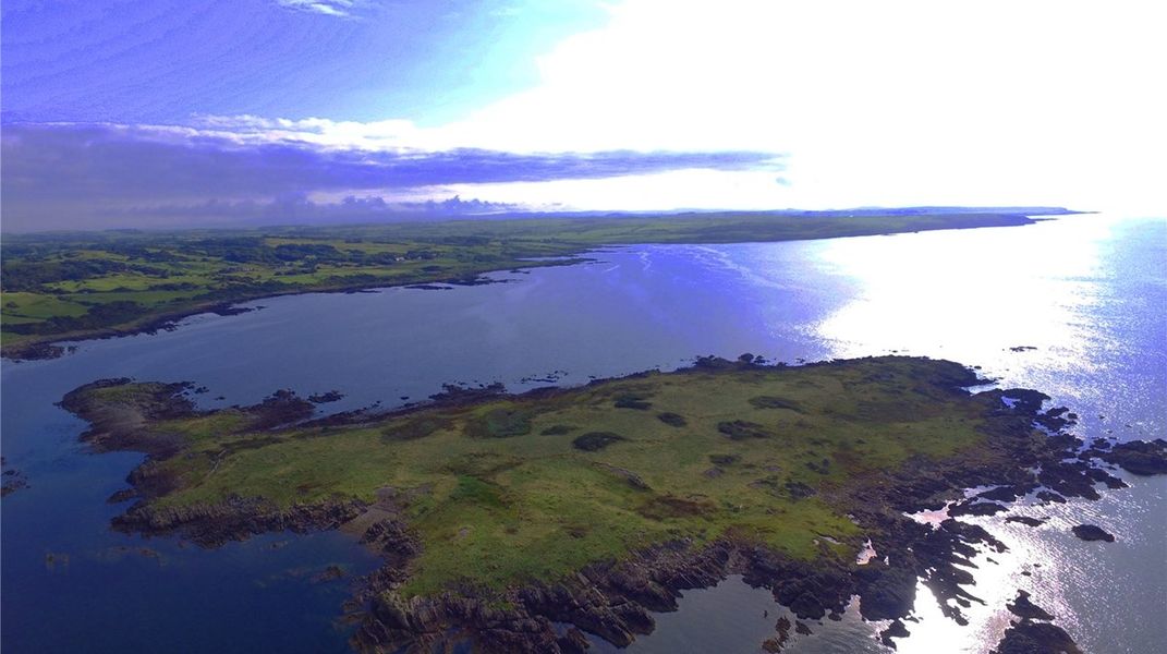 Green island amid water reflecting the sun