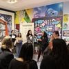 eople stand near a mural by the artist Cita Sadeli, and listen to her talking about why and how she made the mural.