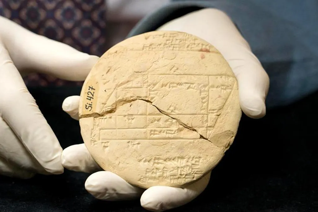 Gloved hands holding cuneiform clay tablet