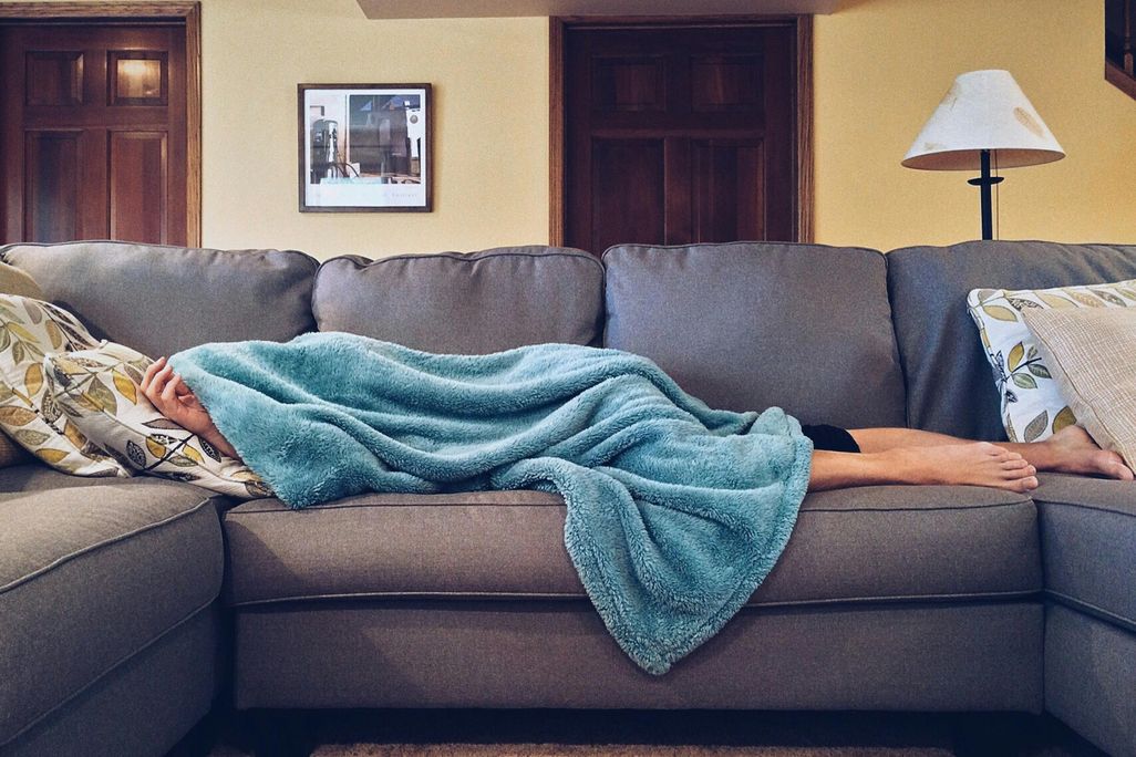 Person napping on the couch under a blanket